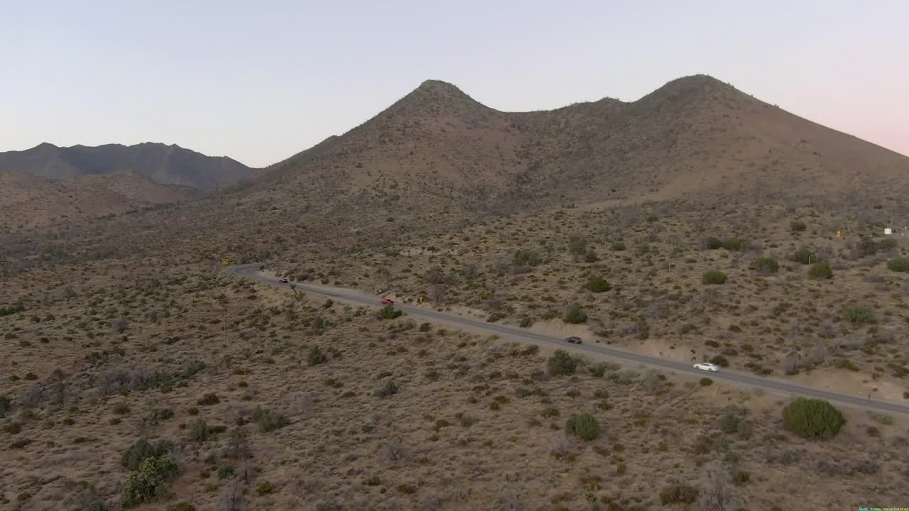 空中平移拍摄的车辆在道路上的山脉对天空，无人机向前飞行的景观在日落-沃克Pass，加利福尼亚视频素材