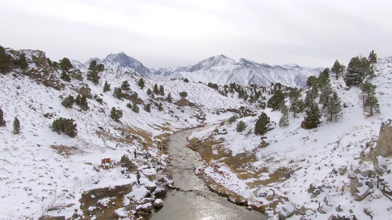 空中放大拍摄的游客在雪山中小溪，无人机飞过人们远足在热溪地质遗址-猛犸湖，加利福尼亚视频素材