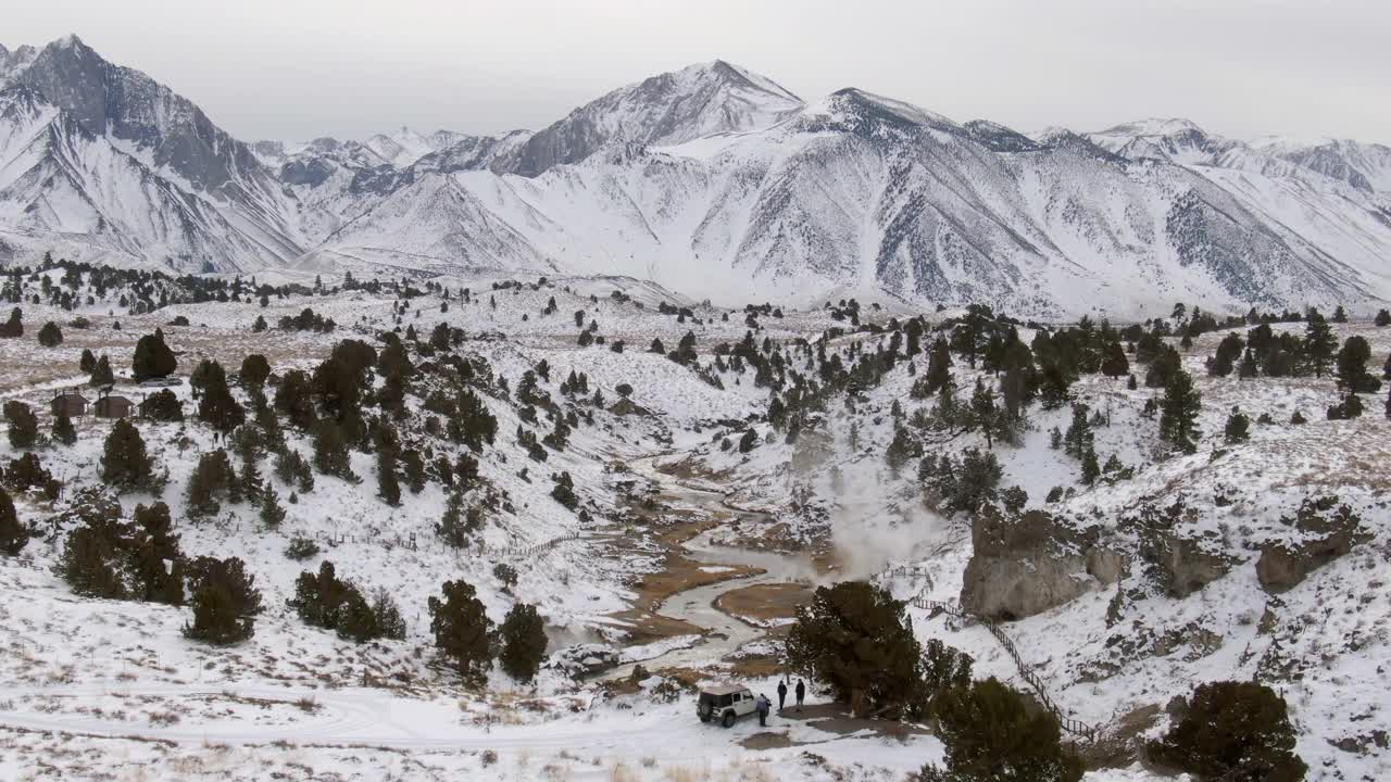 空中拍摄的小溪在雪顶山脉，无人机下降向前的游客徒步在热溪地质遗址-猛犸湖，加利福尼亚视频素材