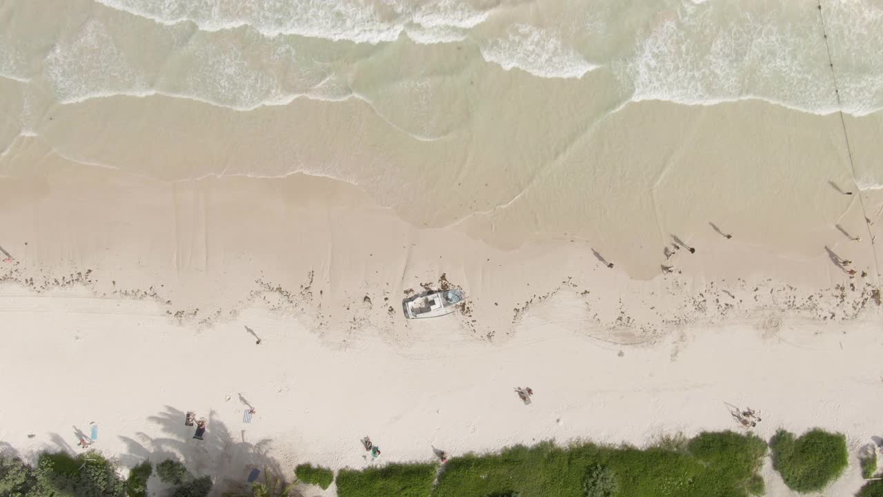 空中倾斜在阳光明媚的一天，在海滩上的人和船失事的照片，无人机向前飞行在海浪拍打海岸对天空-墨西哥图卢姆视频素材