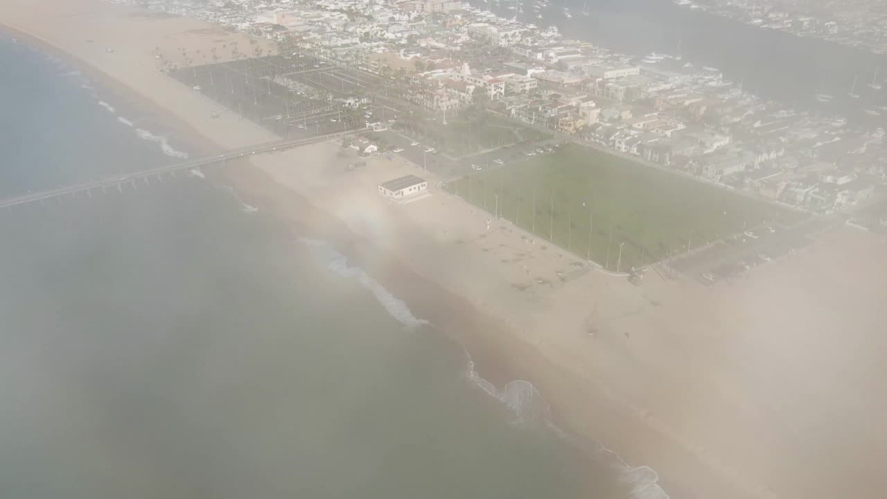 空中倾斜拍摄巴尔波亚码头在城市的海滩在阳光明媚的一天，无人机从房子向后飞对天空-新港海滩，加利福尼亚视频素材