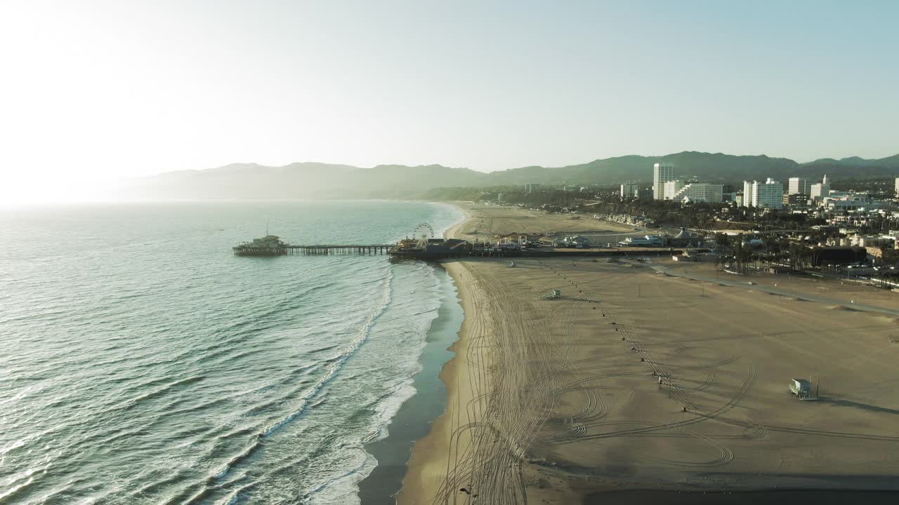 航拍著名的圣塔莫尼卡码头在日落时，无人机飞向海上的地标对天空视频素材