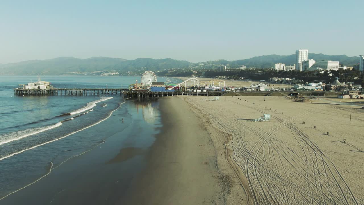 航拍在海滩上著名的码头附近的山，无人机飞过海岸对晴朗的天空在早晨-圣塔莫尼卡，加利福尼亚视频素材