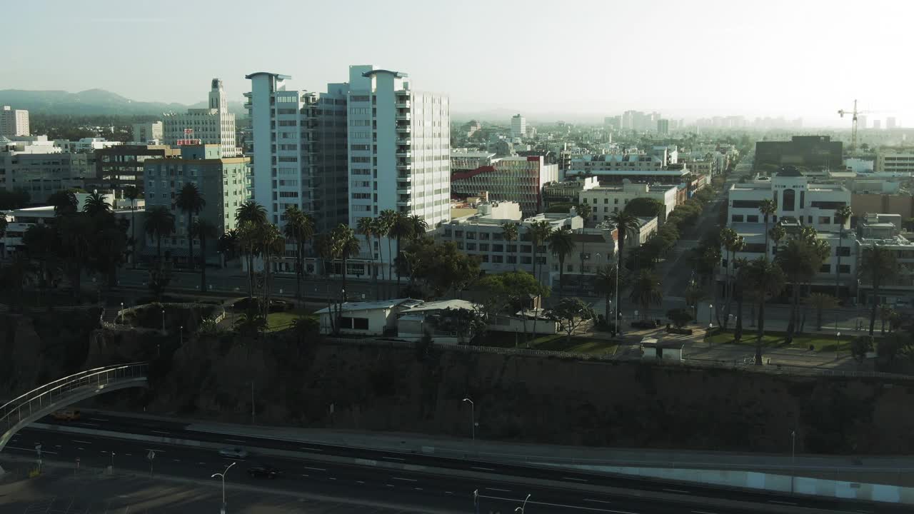 空中拍摄的车辆在街道上的建筑物在城市，无人机向前飞行的城市景观对天空在早晨-圣塔莫尼卡，加利福尼亚视频素材