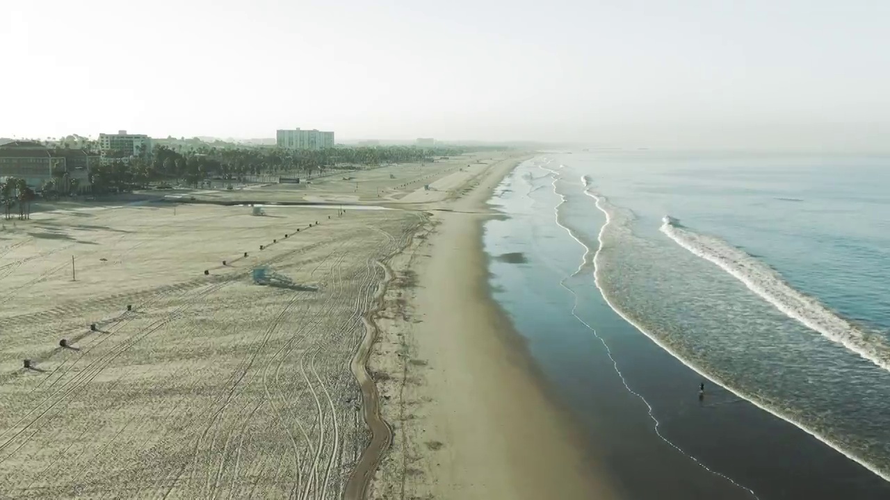 海浪拍打海岸在海滩上的空中拍摄，无人机向前飞行的海岸线在早上-圣塔莫尼卡，加利福尼亚视频素材