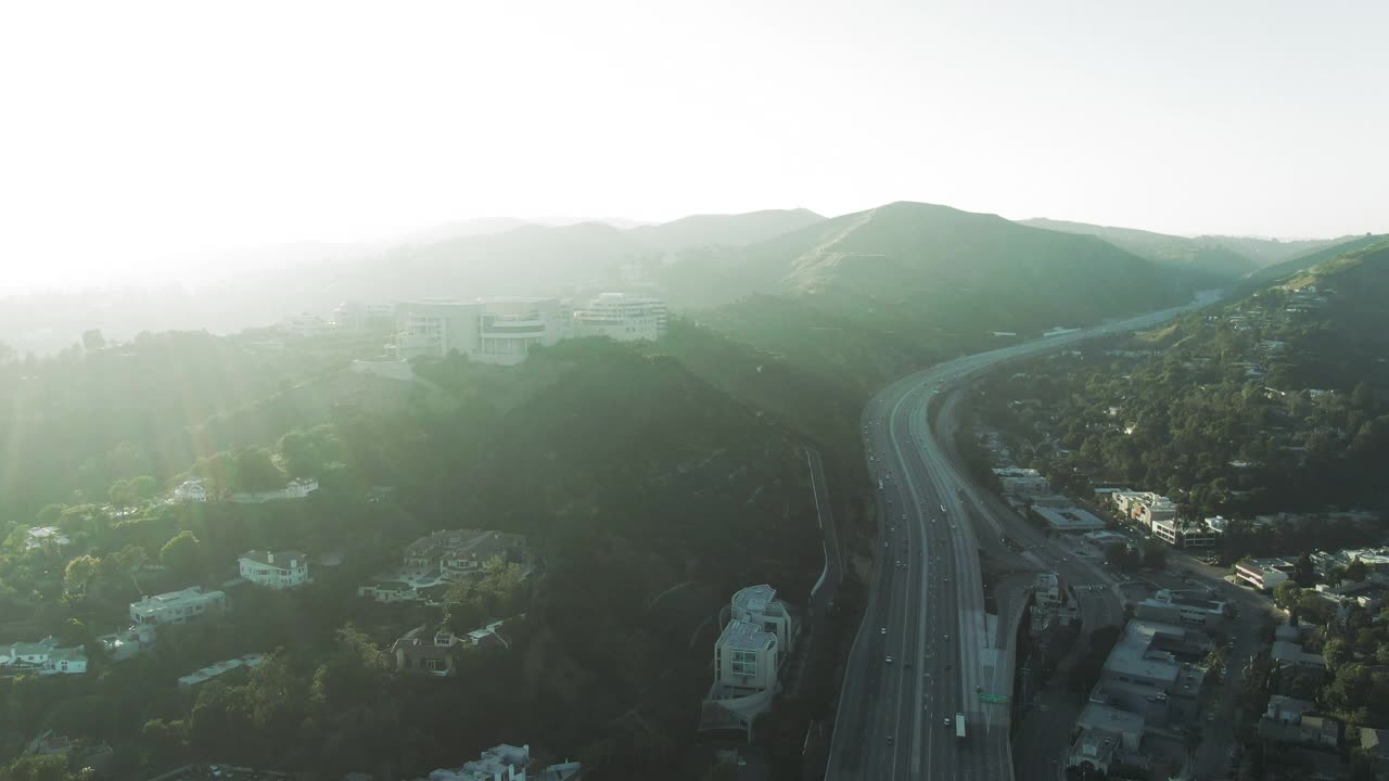 空中封锁拍摄的高速公路上的交通，由著名的盖蒂中心在山上，无人机在日落时分飞过博物馆上空-加州洛杉矶视频素材