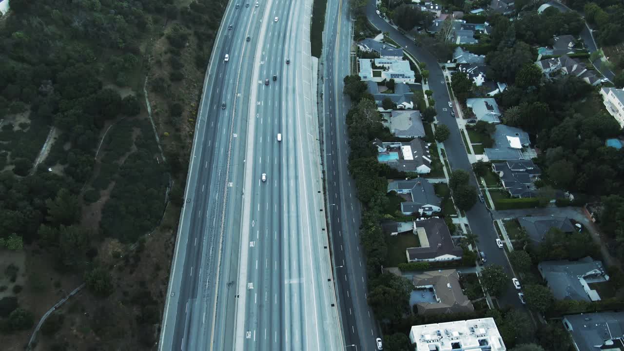 高空倾斜拍摄的高速公路上的交通在山上在日落，无人机向前飞行的车辆对天空-洛杉矶，加利福尼亚视频素材