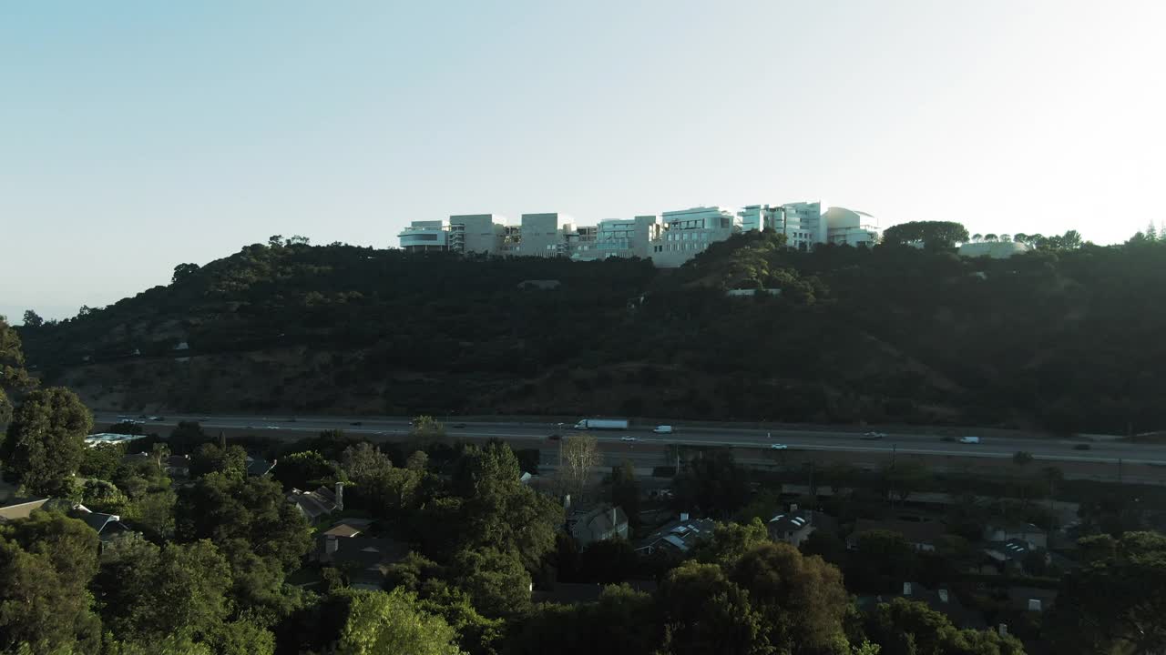 航拍高速公路上的交通由著名的盖蒂中心在山上，无人机在日落时朝着博物馆的天空飞行-洛杉矶，加利福尼亚视频素材