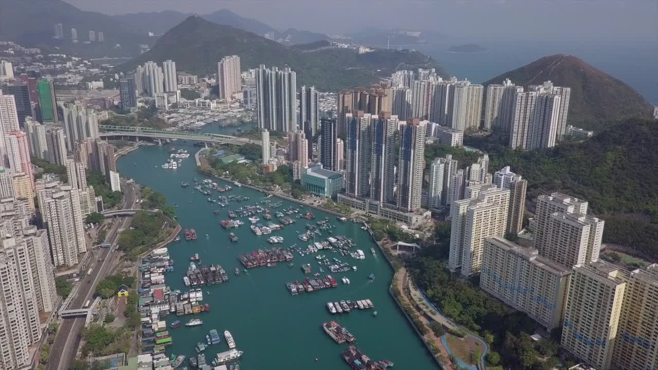 空中倾斜拍摄在高层公寓大楼中海上的船只，无人机飞过城市附近的山区住宅结构-香港，中国视频素材