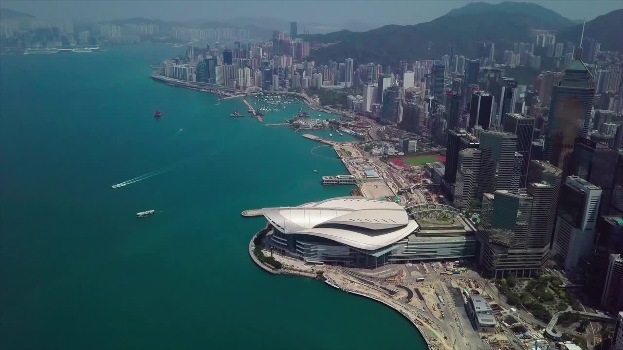 航拍香港会议展览中心，在阳光明媚的日子，无人机在近山的现代城市上空飞行视频素材