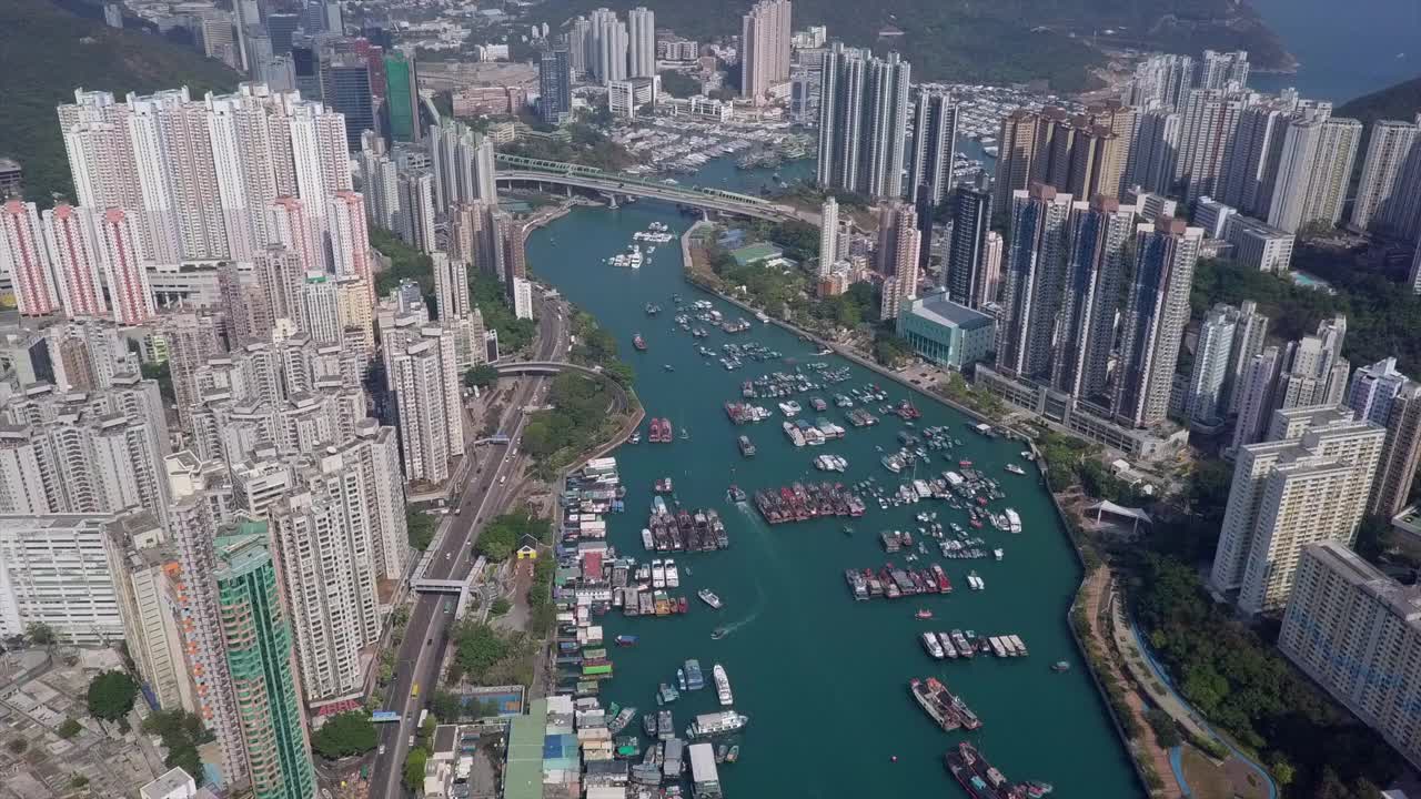 空中封锁拍摄在高楼大厦中海上的船只，无人机在靠近山区的城市的住宅建筑上空飞行-中国香港视频素材