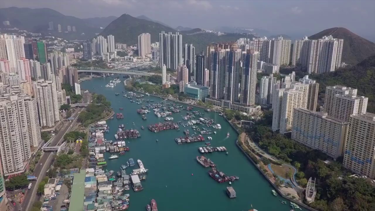 航拍在高高的公寓大楼中海上的船只，无人机飞过城市附近的山区的住宅结构-香港，中国视频素材