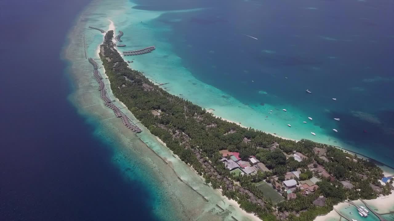 空中向上倾斜拍摄的蓝色海洋周围的岛屿度假胜地在晴朗的一天，无人机向前飞行在水上小屋对天空-南马莱环礁，马尔代夫视频素材