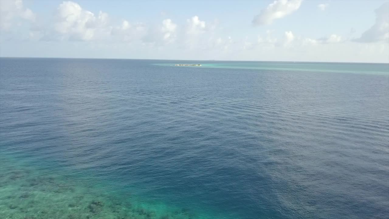 航拍美丽的岛屿在海上对天空在晴朗的一天，无人机向前飞行的海景-南马累环礁，马尔代夫视频素材