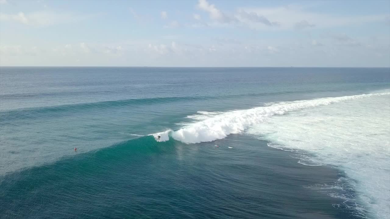 空中拍摄的人冲浪在海浪上对着天空，无人机向后飞溅水-南马累环礁，马尔代夫视频素材