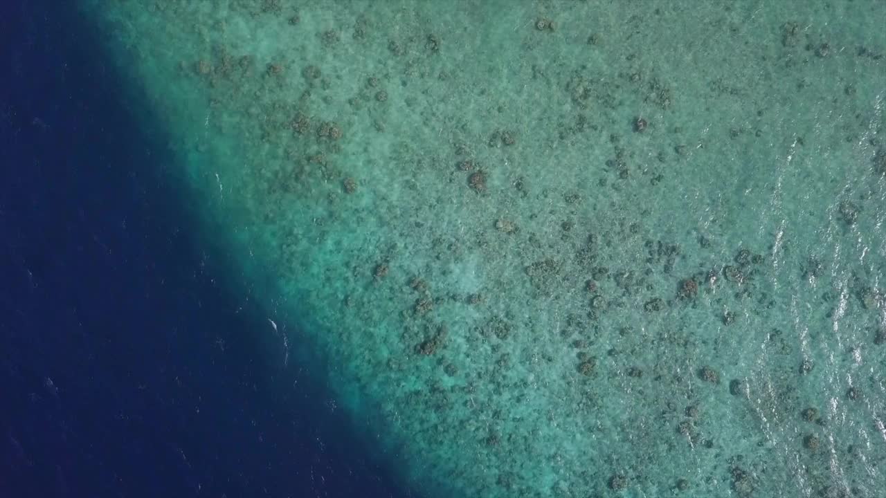 鸟瞰图的岩石形成在绿松石海，无人机向前飞行在阳光明媚的一天-南马莱环礁，马尔代夫视频素材