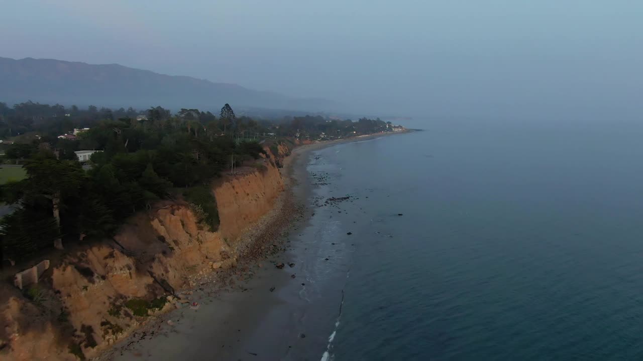 空中拍摄的蝴蝶海滩悬崖对天空，无人机下降在海浪溅在海岸在日落-圣巴巴拉，加利福尼亚视频素材