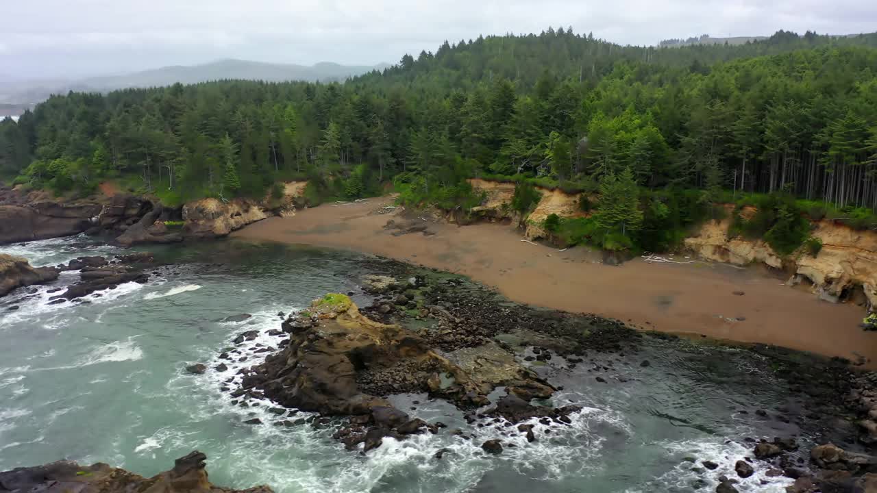 空中平移拍摄的海浪冲向岩石海岸的树木-曼萨尼塔，俄勒冈州视频素材