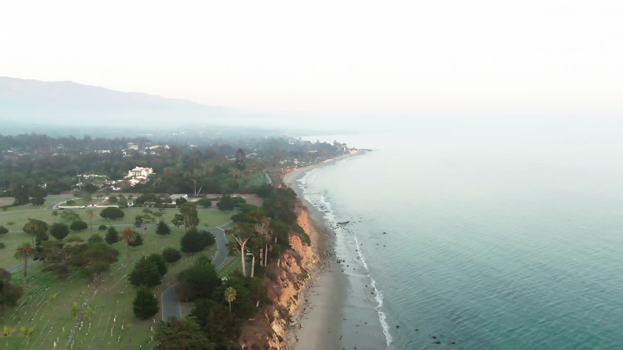 航拍浪花溅在蝴蝶海滩对天空，无人机在日落期间在海岸附近的山飞行向前-圣巴巴拉，加利福尼亚视频素材