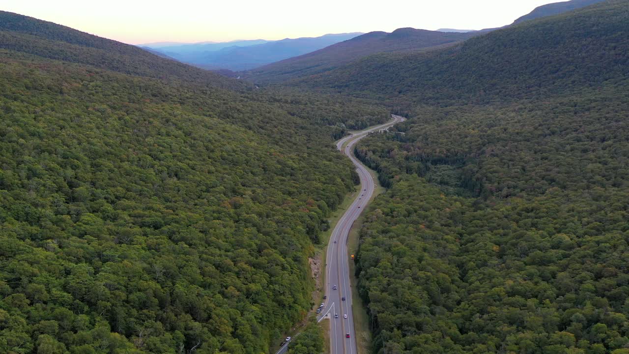 空中拍摄的车辆移动在道路上通过在秋天的森林在山-弗兰科尼亚，新罕布什尔州视频素材