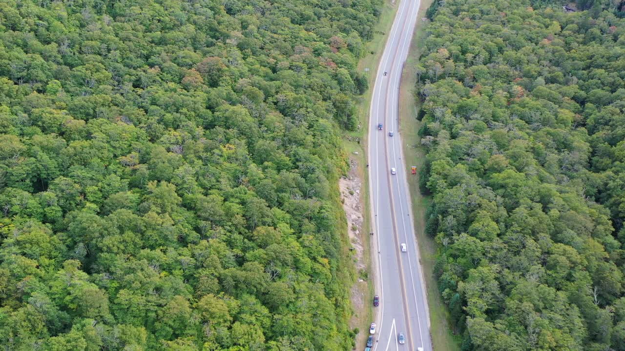 空中拍摄的车辆移动的道路在山上的树木在秋天，无人机向后飞行-弗兰科尼亚，新罕布什尔州视频素材