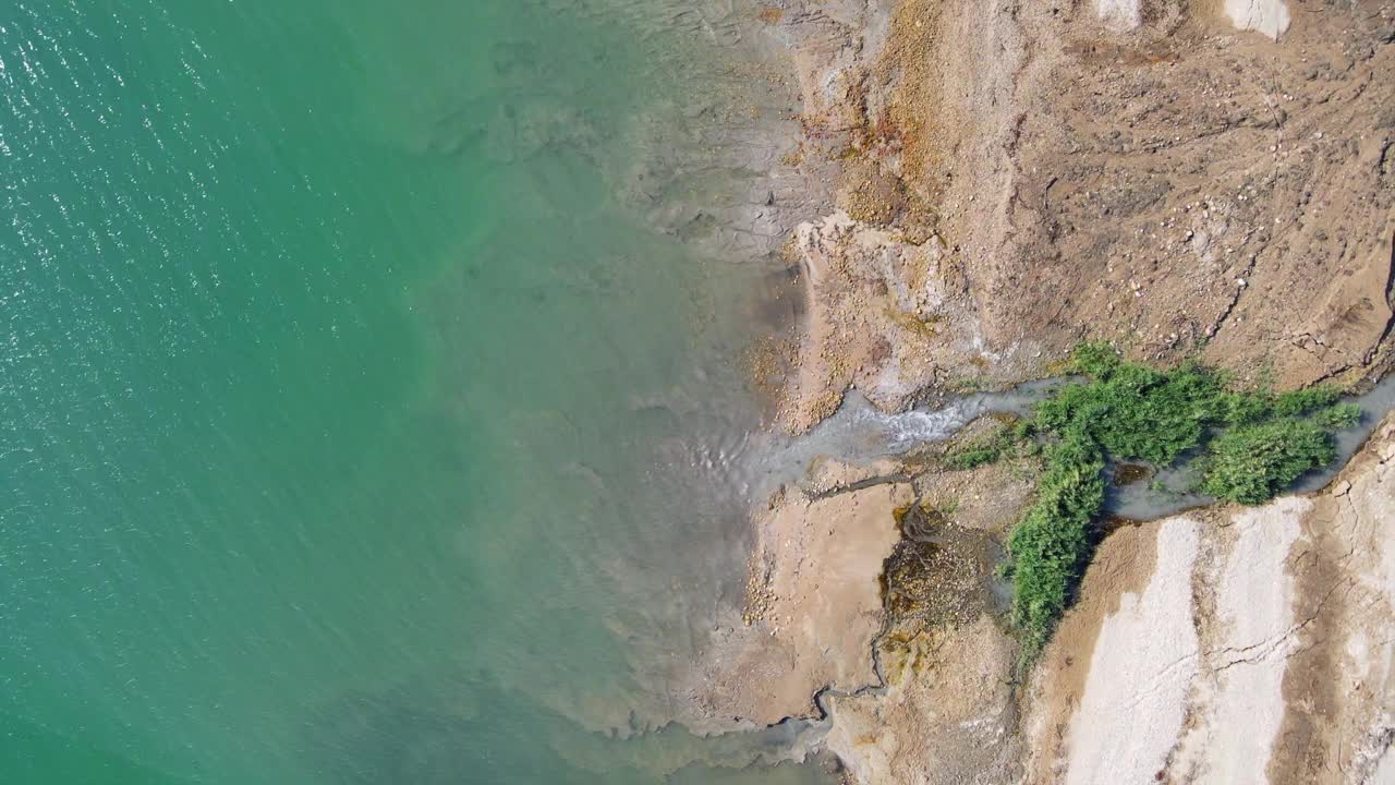 空中拍摄的小溪流动在海岸线在晴朗的一天，无人机在水上-死海，以色列视频素材