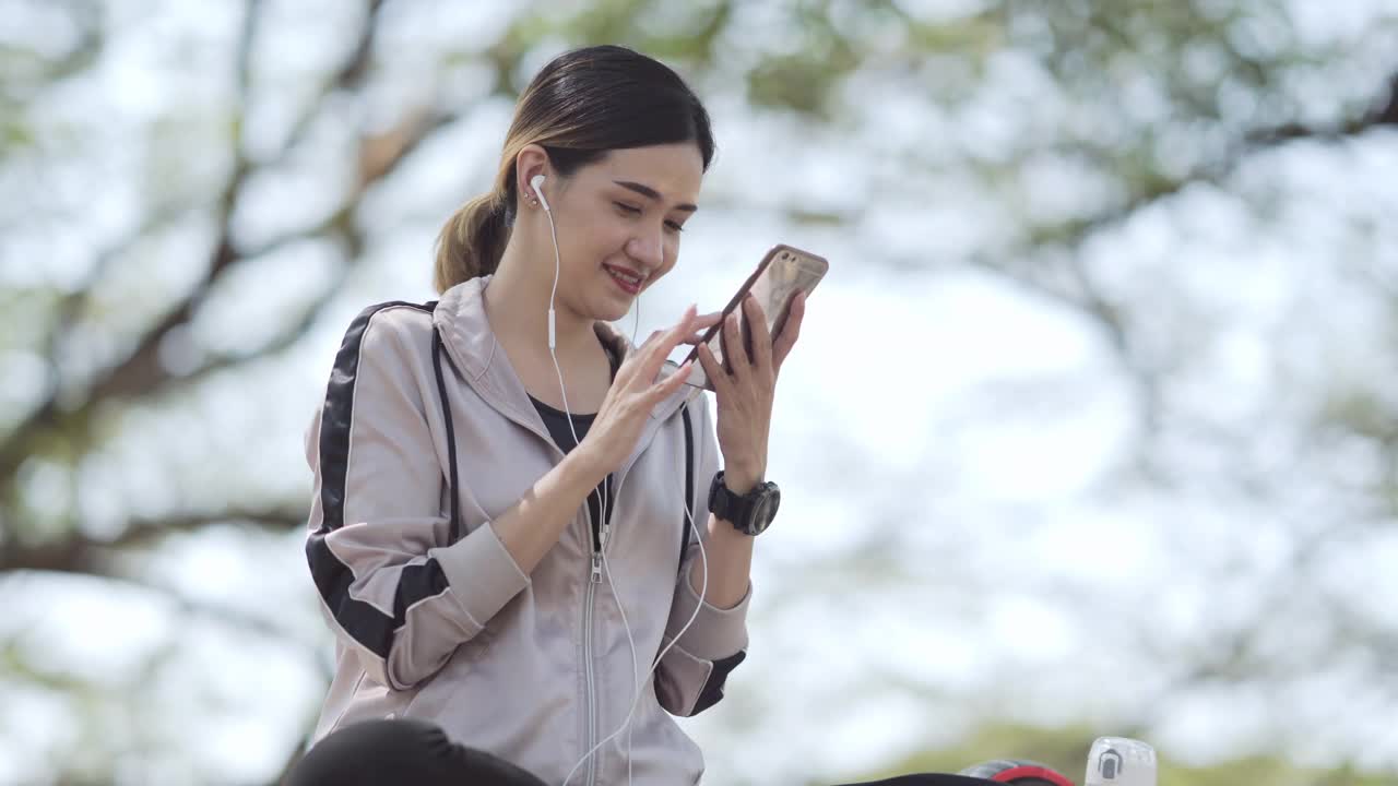 年轻女子穿着运动服在手机上听音乐视频素材