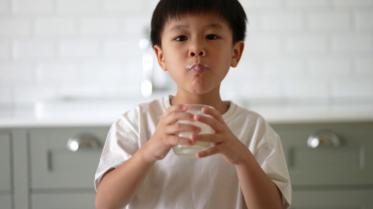 亚洲小孩早餐喝一杯牛奶。健康早餐的概念视频素材