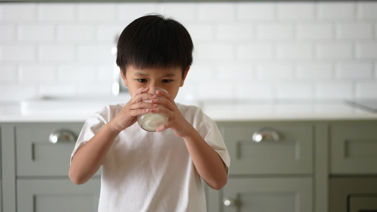 亚洲小孩早餐喝一杯牛奶。健康早餐的概念视频素材