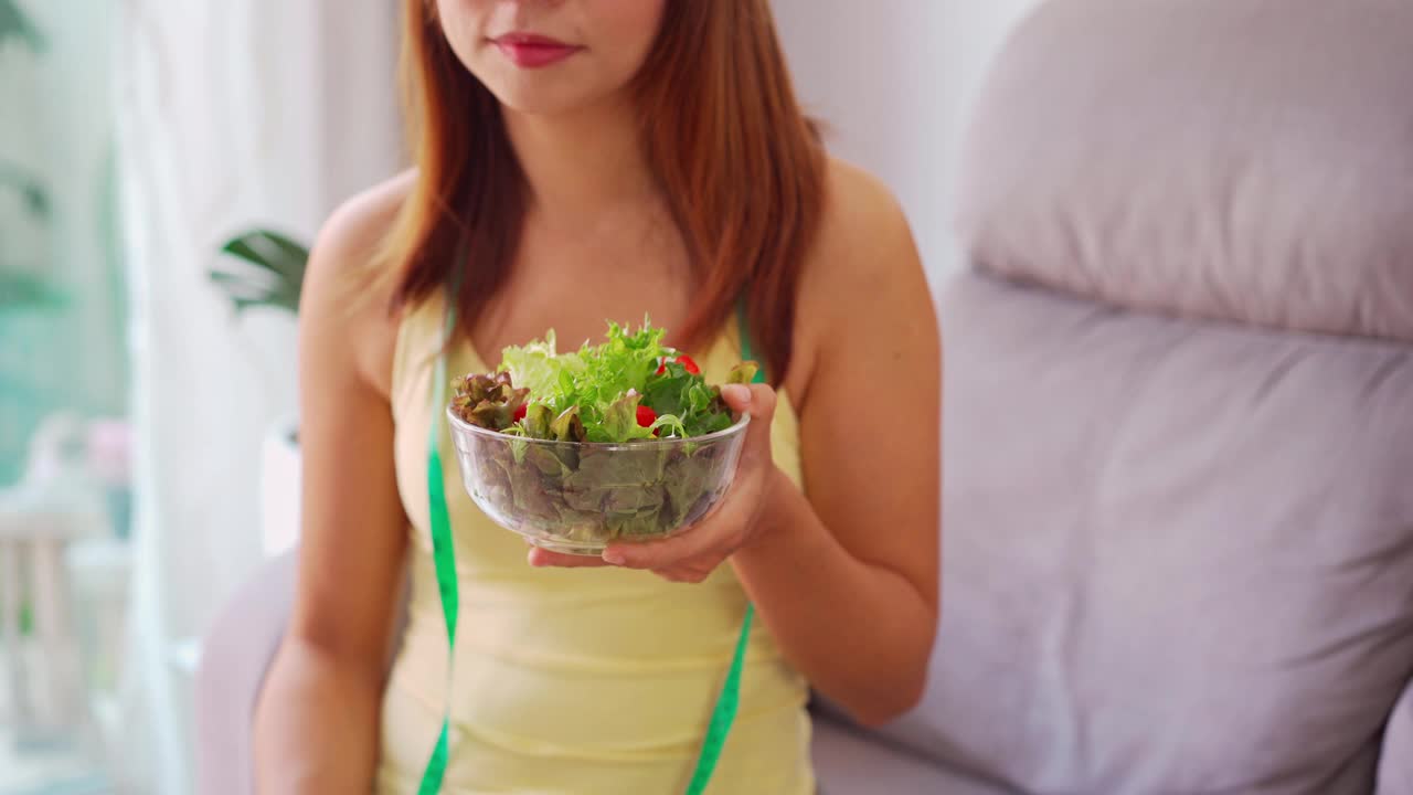 年轻女子用自制的健康沙拉和哑铃在家锻炼，健康的饮食生活方式和饮食理念视频素材