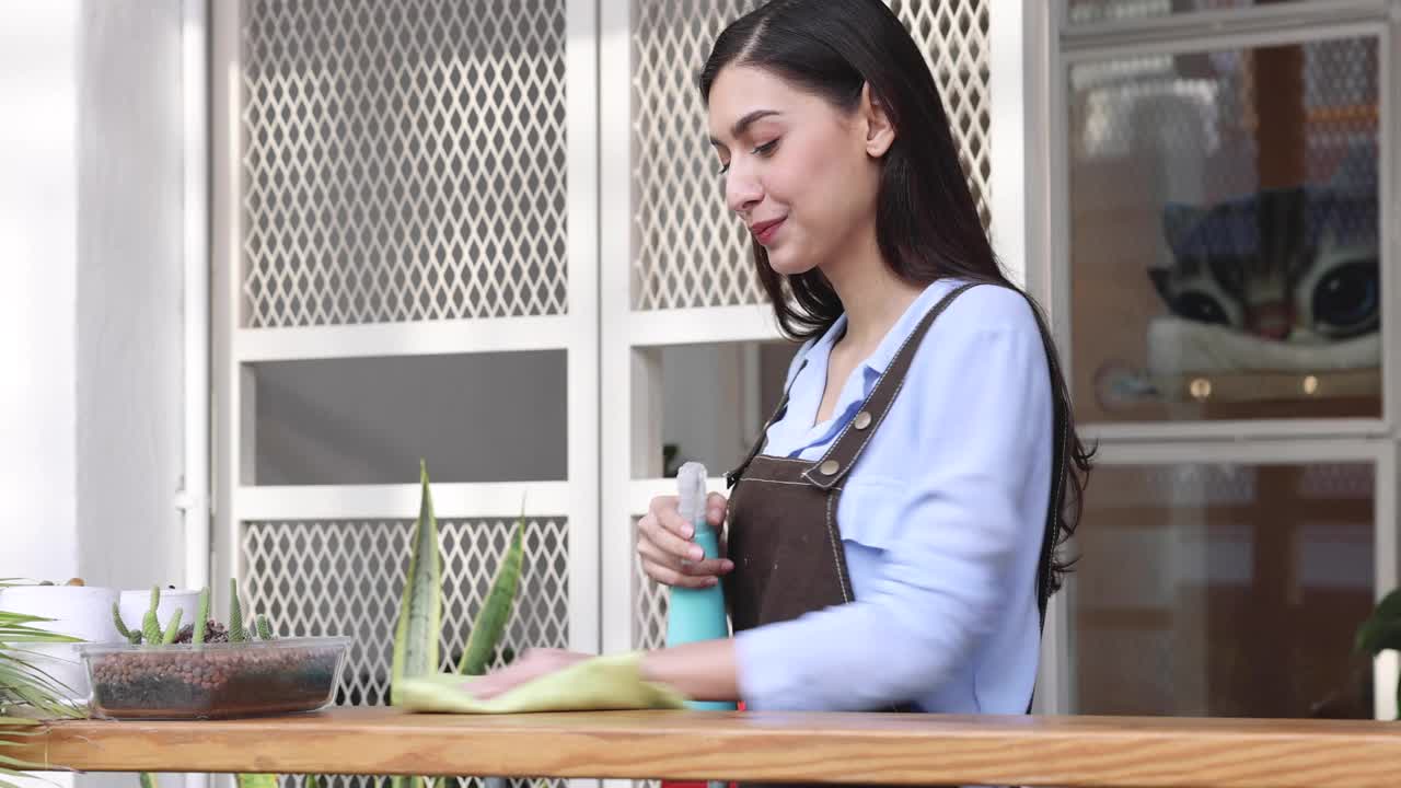 快乐的女员工打扫餐厅，她用喷雾和抹布擦拭脏桌子上的灰尘。视频素材