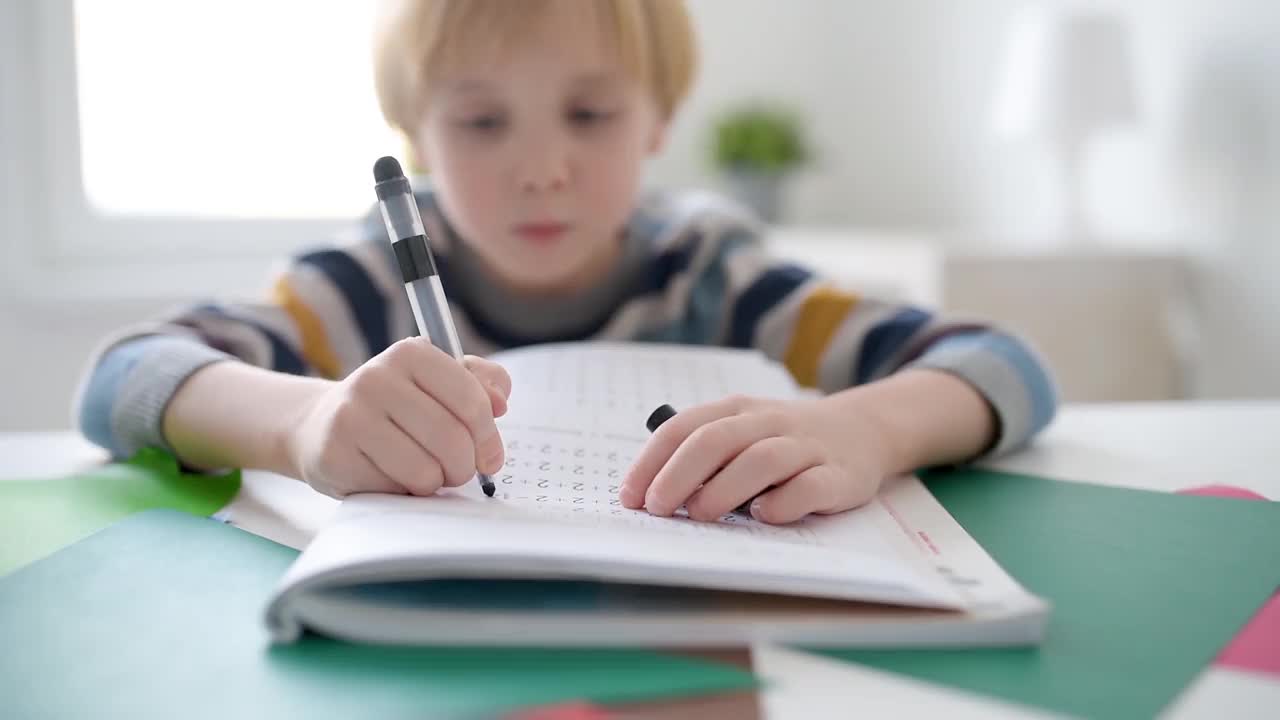 小学生在家里做作业。孩子学习数数，解决算术例子，做练习册上的练习。数学教程。为学龄前婴儿上学做准备。教育视频素材