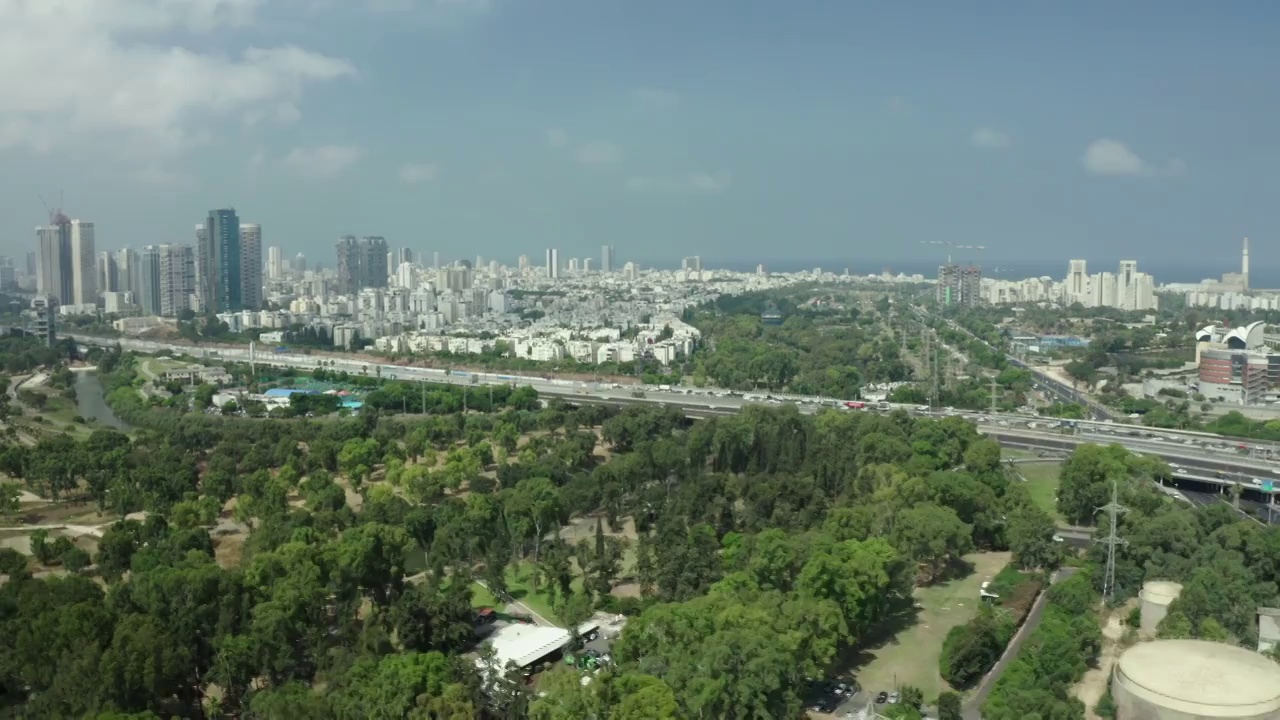 空中拍摄的道路在城市里美丽的Yarkon公园，无人机在树上移动-特拉维夫，以色列视频素材