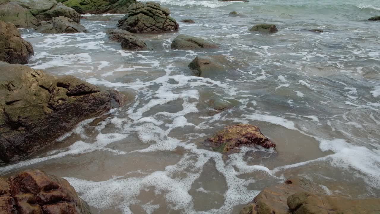 在有许多岩石的海滩上，海浪不停地拍打着海岸。视频素材