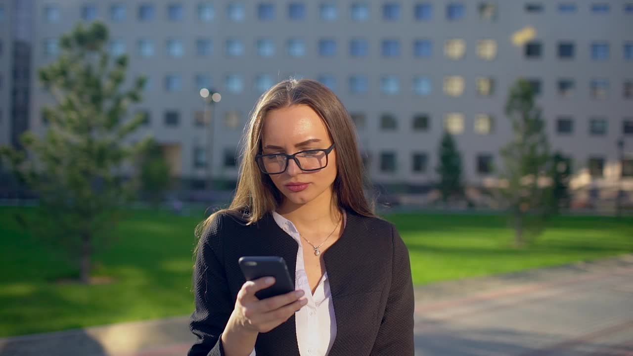 年轻成功的职业女性、商人或女学生在户外使用手机、智能手机并收到好消息激动高兴视频素材