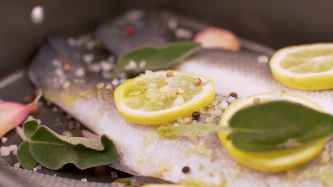 新鲜的海鲈鱼与柠檬片和鼠尾草一起在平底锅中烹煮视频素材