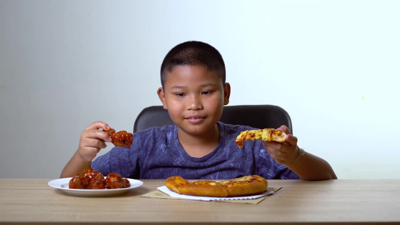 亚洲胖男孩选择了披萨和炸鸡。概念致病性食品的儿童健康问题。视频素材