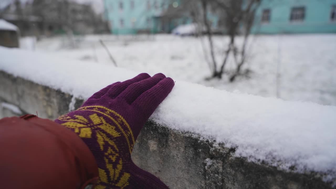 那家伙用手从篱笆上耙雪。射击戴着手套的手视频素材