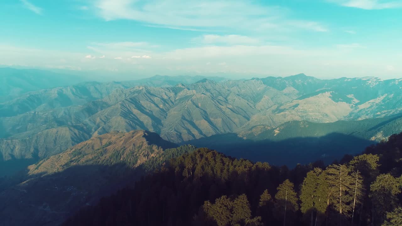 美丽的空中鸟瞰图山脉对多云的蓝天被高大的绿色松林包围视频素材