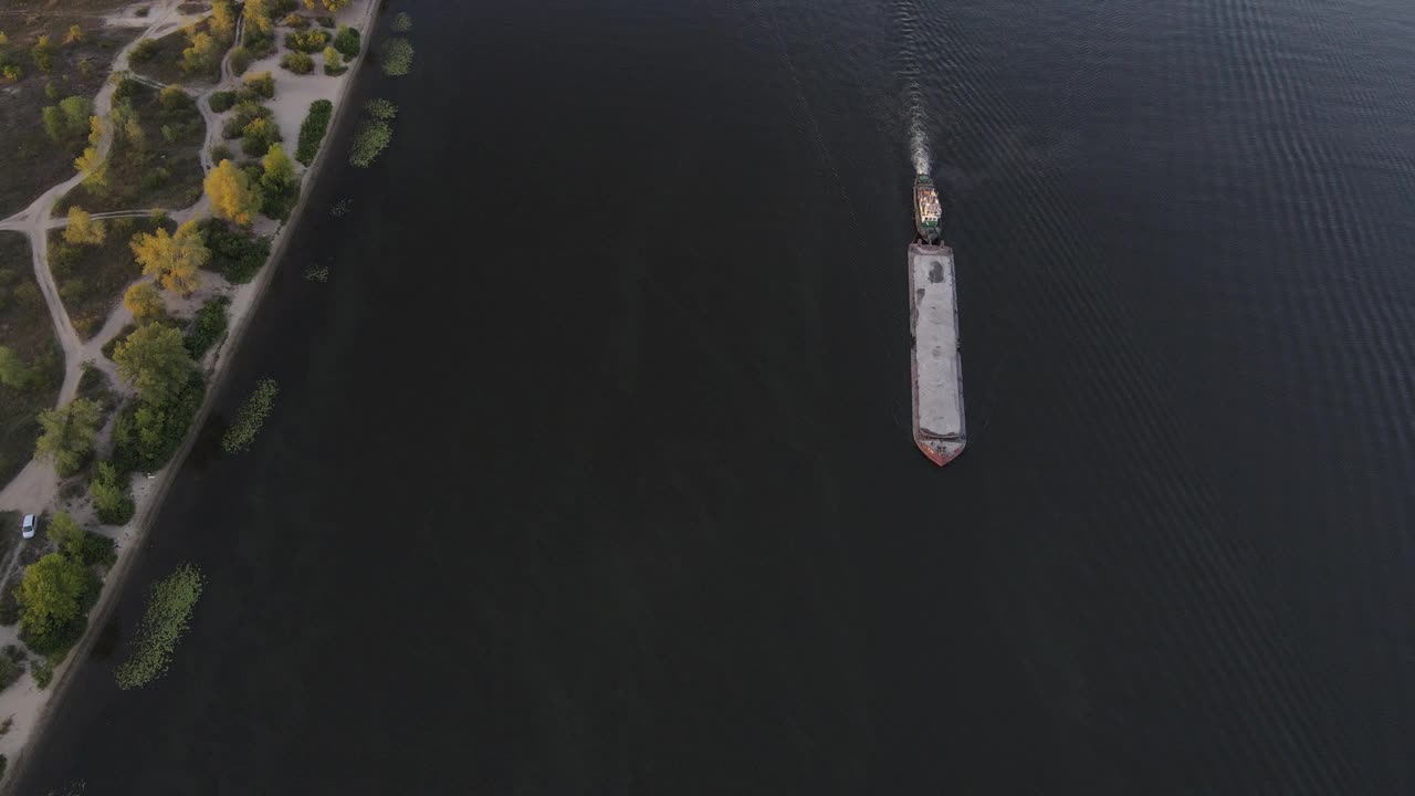 一艘沙驳船在靠近海岸的一条河上航行的鸟瞰图视频素材