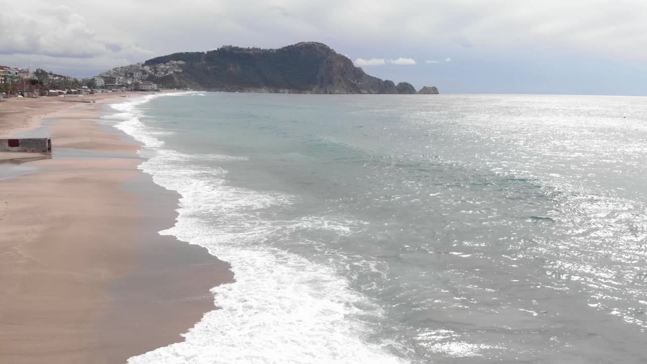 空旷的海滩，美丽的海浪拍打着沙滩。鸟瞰图的海岸线与巨大的蓝色海浪创造白色泡沫视频素材