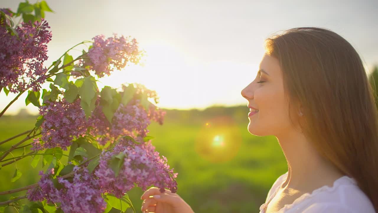 年轻浪漫的微笑美丽的女人女孩嗅闻丁香花在一束日落自然视频素材