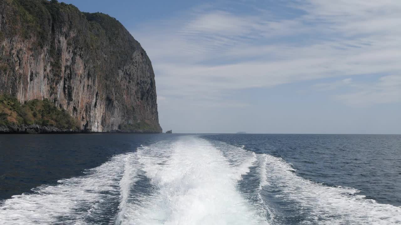 从岛上看船的后部。快艇后面的波浪掠过海面，慢镜头视频素材