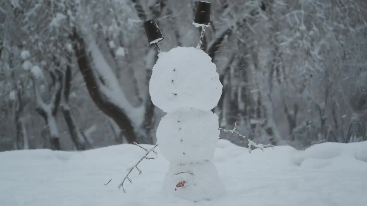 快乐滑稽的雪人杂技演员倒立在头上，背景是一场强降雪。视频素材