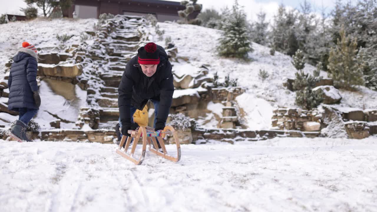 冬天的一天，一个老人在后院拉雪橇视频素材