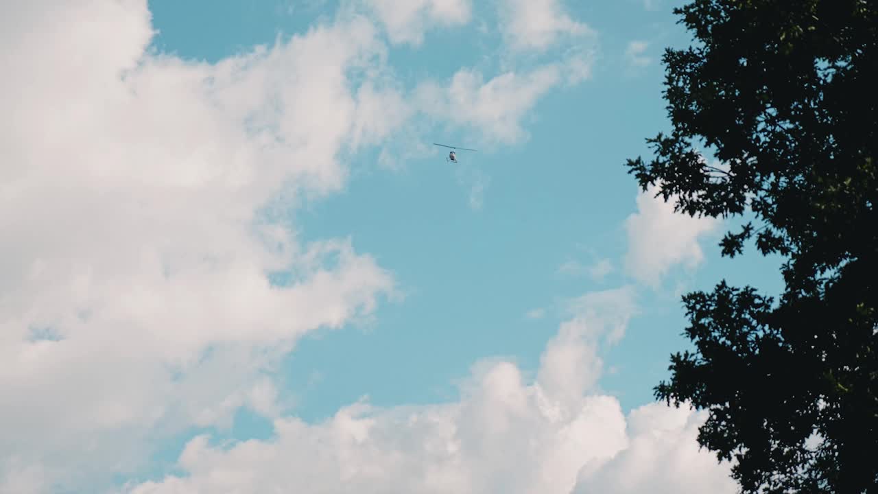 一架直升飞机在森林上空飞行。从地面射击。摄影机跟随直升机。视频素材