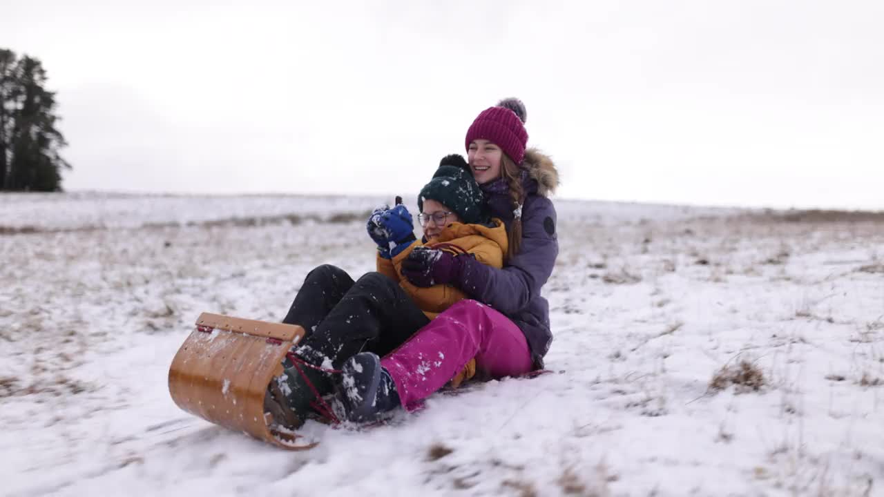 哥哥和妹妹在冬天的一天在山上玩雪橇视频素材