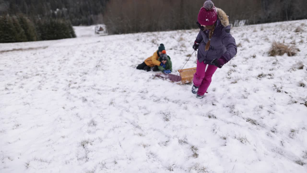 冬天的一天，三个孩子在山上滑雪橇视频素材