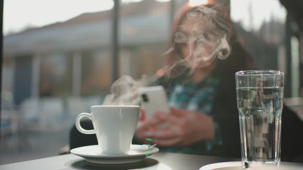 在等待咖啡冷却的时候，女人用手机上网视频素材