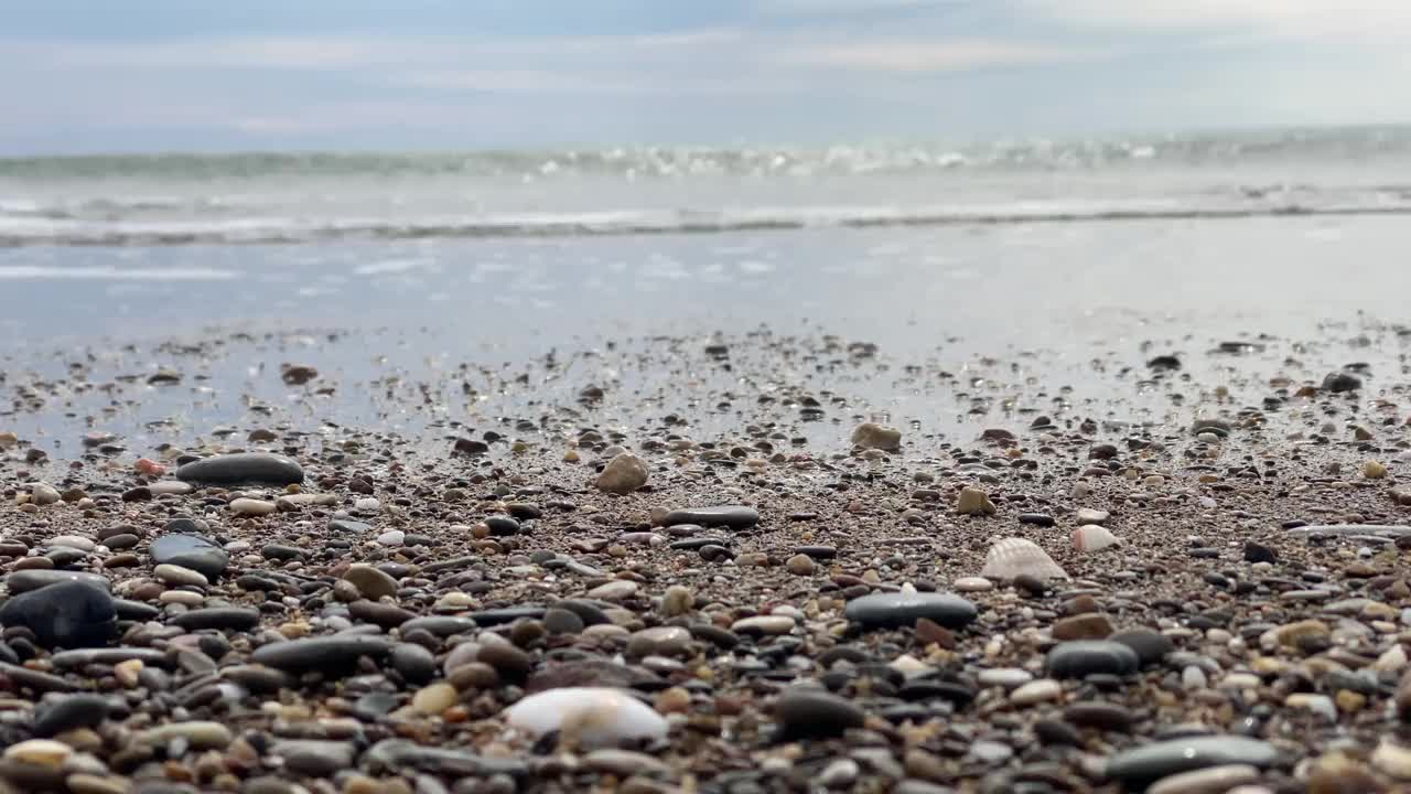 沙滩上的鹅卵石和海里的波浪。视频素材